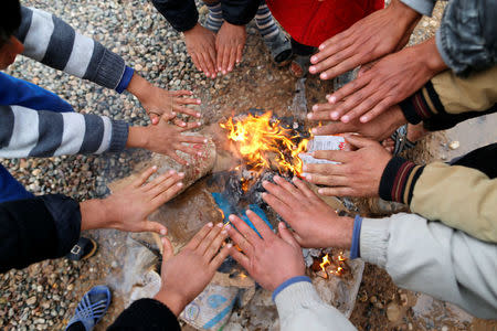 Displaced Iraqi boys, who fled the Islamic State stronghold of Mosul, warm themselves by a fire in Khazer camp, Iraq. REUTERS/Ammar Awad