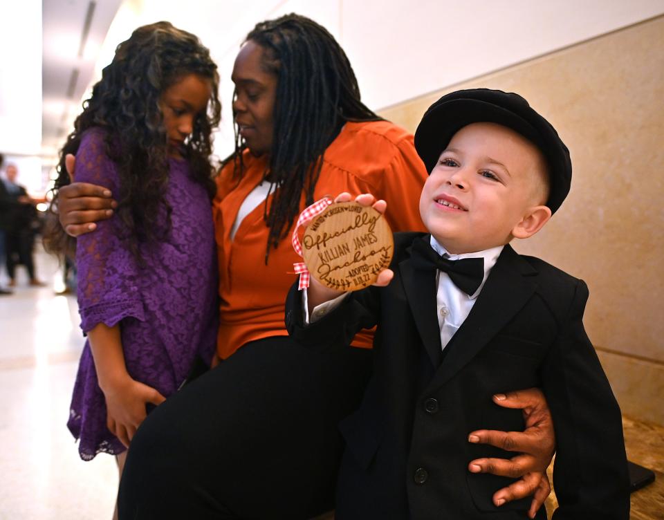 Killian Jackson, 5, of Hardwick, shows off his adoption ornament while sitting with his new mother, Charlene Jackson, and sister Layla, 8, during Friday's 20th annual National Adoption Day at Worcester Juvenile Court.