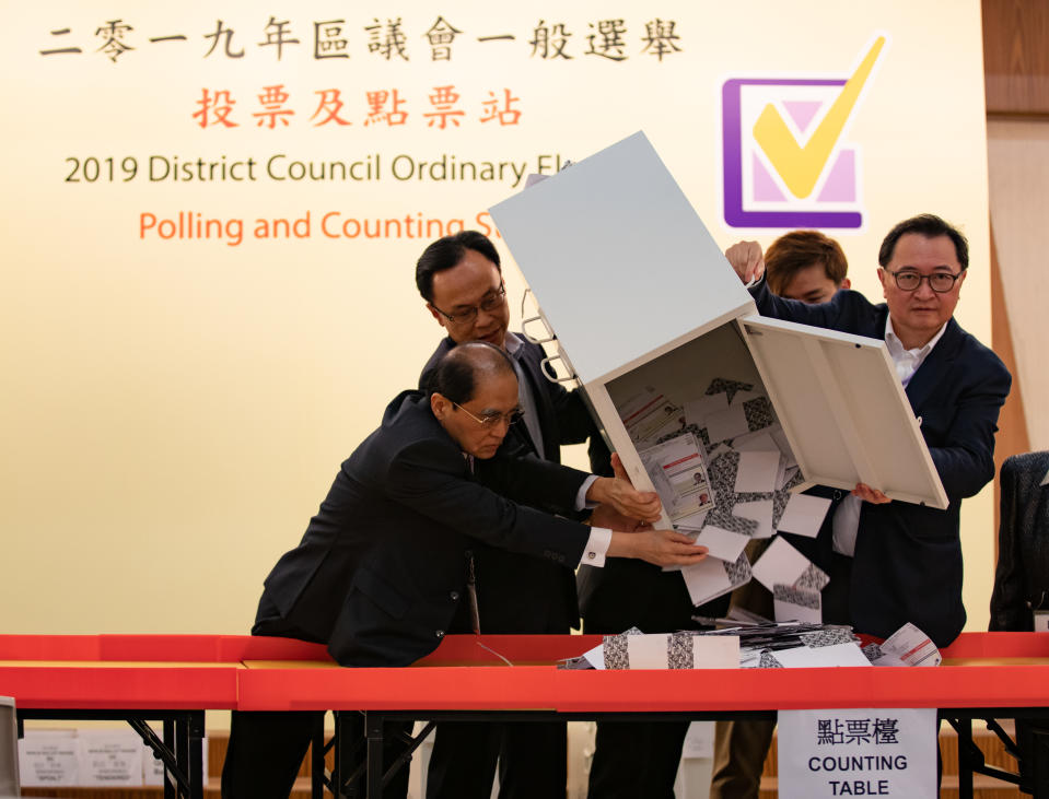 HONG KONG, CHINA - 2019/11/24: The Chairman of the HKSAR Electoral Affairs Commission (EAC), Barnabas Fung (second from the right) pours down the ballots from a ballot box to be counted at a polling station. Nearly 3 million Hong Kong citizens cast their ballots on Sundays district council elections in the referendum race between the pro-democracy camp and pro-Beijing camp after more than five months of turmoil in the city. The turnout was confirmed with at least 71.2% of 4.1 million registered to vote. (Photo by May James/SOPA Images/LightRocket via Getty Images)