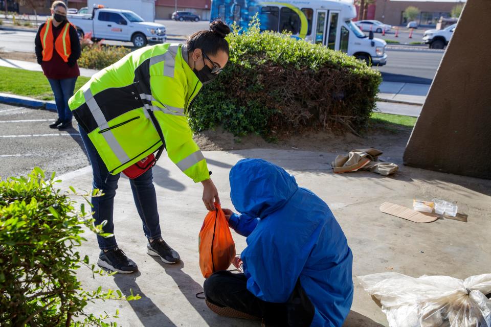 City of Indio employee Yanel Ramirez gives a person experiencing homelessness a bag of supplies during the annual Riverside County point-in-time homeless count in Indio, Calif., on Wednesday, Feb. 23, 2022. 