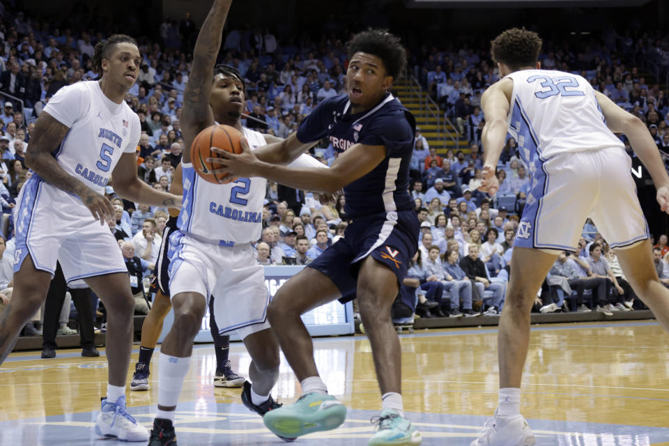 Virginia guard Reece Beekman, second from right, is defended by North Carolina forward Armando Bacot (5), guard Caleb Love (2) and forward Pete Nance (32) during the second half of an NCAA college basketball game Saturday, Feb. 25, 2023, in Chapel Hill, N.C. (AP Photo/Chris Seward)