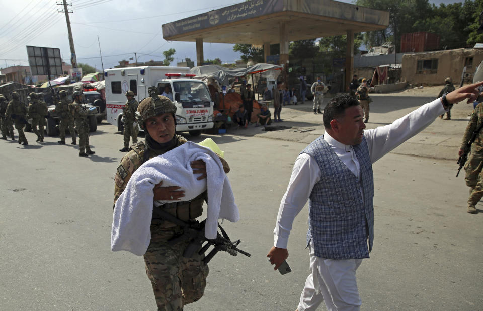 FILE - In this May 12, 2020 file photo, an Afghan security officer carries a baby after an attack by gunmen on a maternity hospital that killed 24 people, in the Afghan capital Kabul. Afghanistan is supposed to be moving toward peace. But Kabul's residents fear the frequent bombings in the past months, large-scale attacks, kidnappings for ransom, armed men in broad daylight robbing stores, people in parks and cars stuck in traffic, are a sign it is instead entering yet another phase in decades of war. (AP Photo/Rahmat Gul, File)