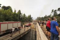 Local residents gather at a forest during a wildfire near Kechries village on the island of Evia, about 144 kilometers (90 miles) north of Athens, Greece, Thursday, Aug. 5, 2021. Forest fires fueled by a protracted heat wave raged overnight and into Thursday in Greece, threatening the archaeological site at the birthplace of the modern Olympics and forcing the evacuation of dozens of villages. (AP Photo/Thodoris Nikolaou)