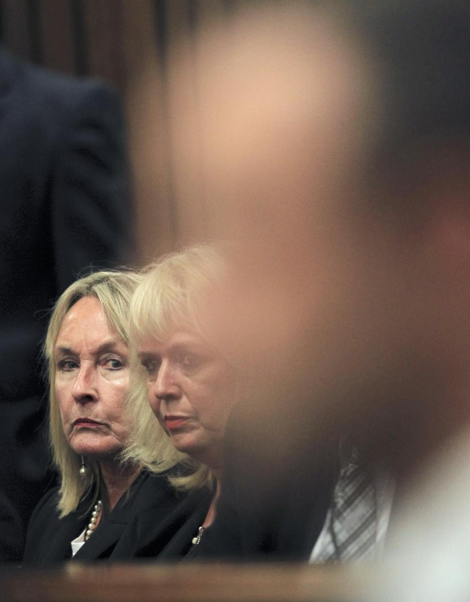 June Steenkamp (L), the mother of Reeva Steenkamp, glances at Oscar Pistorius as he sits in the dock ahead of the trial of the Olympic and Paralympic track star at the North Gauteng High Court in Pretoria March 3, 2014. "Blade Runner" Pistorius arrived at the Pretoria High Court on Monday for the start of his murder trial, opening a decisive chapter in the story of the rise and fall of one of the world's best-known athletes. REUTERS/Themba Hadebe/Pool (SOUTH AFRICA - Tags: SPORT ATHLETICS CRIME LAW)