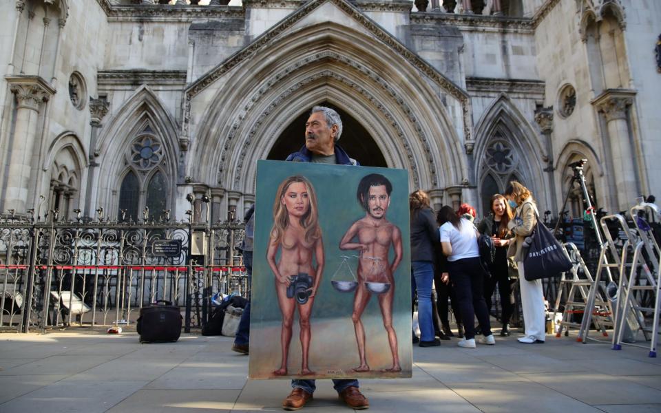 Artist Kaya Mar holds an artwork depicting Johnny Depp and Amber Heard outside the High Court - Aaron Chown/PA