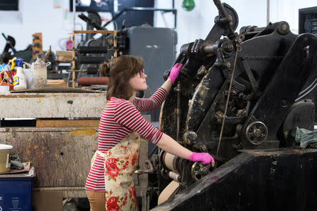 Lottie Small use the die stamping press at the workshop of Barnard and Westwood, who are printing the invitations for Britain's Prince Harry and Meghan Markle's wedding at Windsor Castle in May, London, Britain, March 22, 2018. Victoria Jones/Pool via Reuters