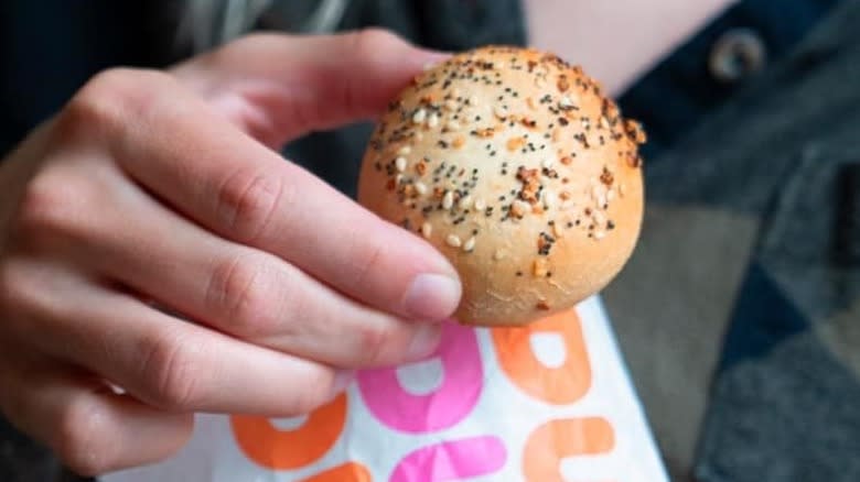 holding Dunkin' stuffed bagel mini