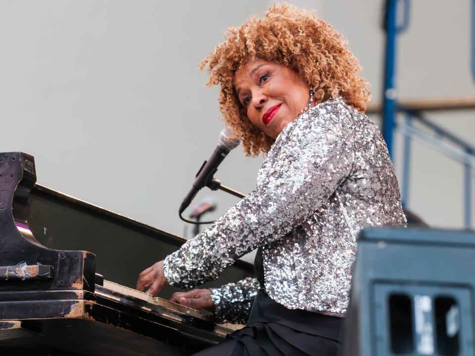 Roberta Flack plays piano while wearing a sparkly silver jacket