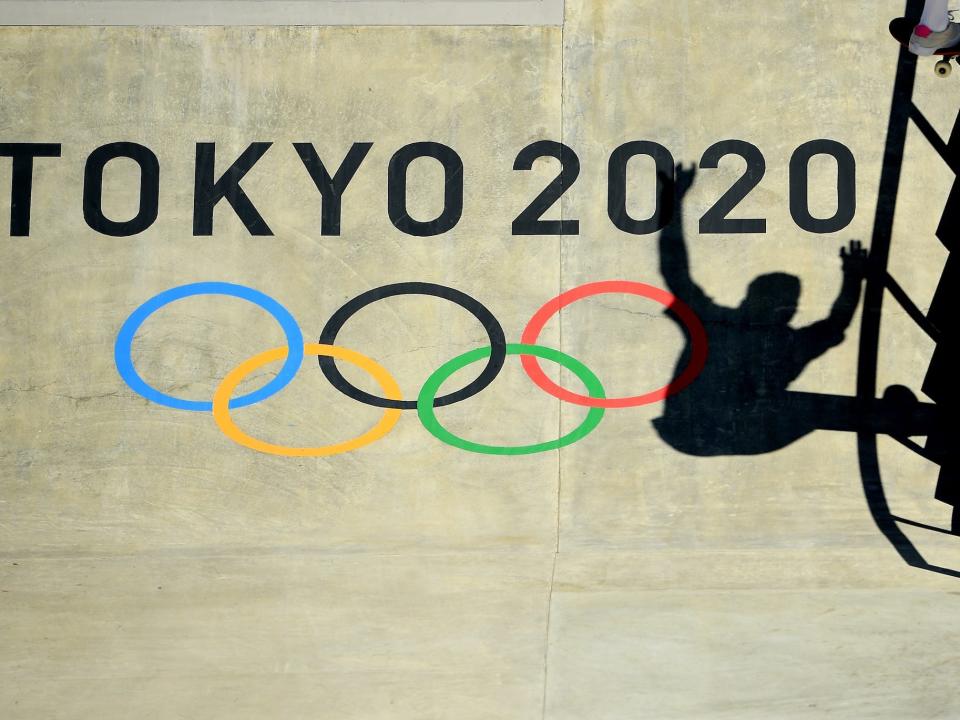 A shadow of a skateboarder over the Tokyo 2020 logo.