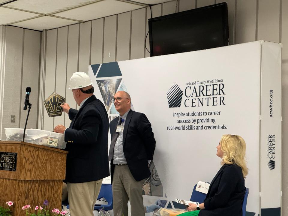 Career Center Principal Rick Brindley takes items out of a time capsule at the groundbreaking and 50th anniversary celebration as Superintendent Rod Cheney and Ohio Statehouse Rep. Melanie Miller look on.