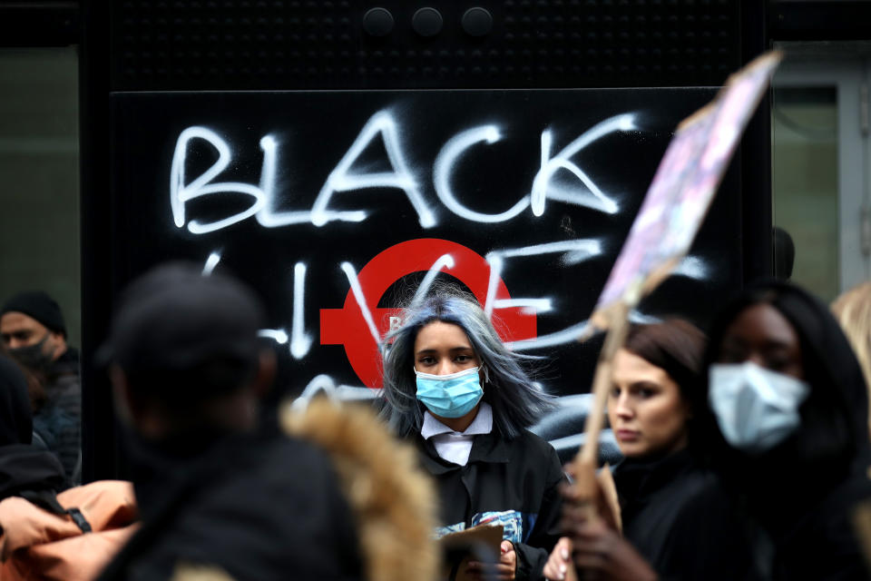 LONDON, UNITED KINGDOM - JUNE 06: Protesters walk past graffiti on a bus stop during a Black Lives Matter protest at Parliament Square on June 06, 2020 in London, United Kingdom. The death of an African-American man, George Floyd, while in the custody of Minneapolis police has sparked protests across the United States, as well as demonstrations of solidarity in many countries around the world. (Photo by Alex Pantling/Getty Images)