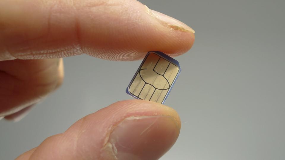 A close up of a SIM card being held between a finger and thumb. 