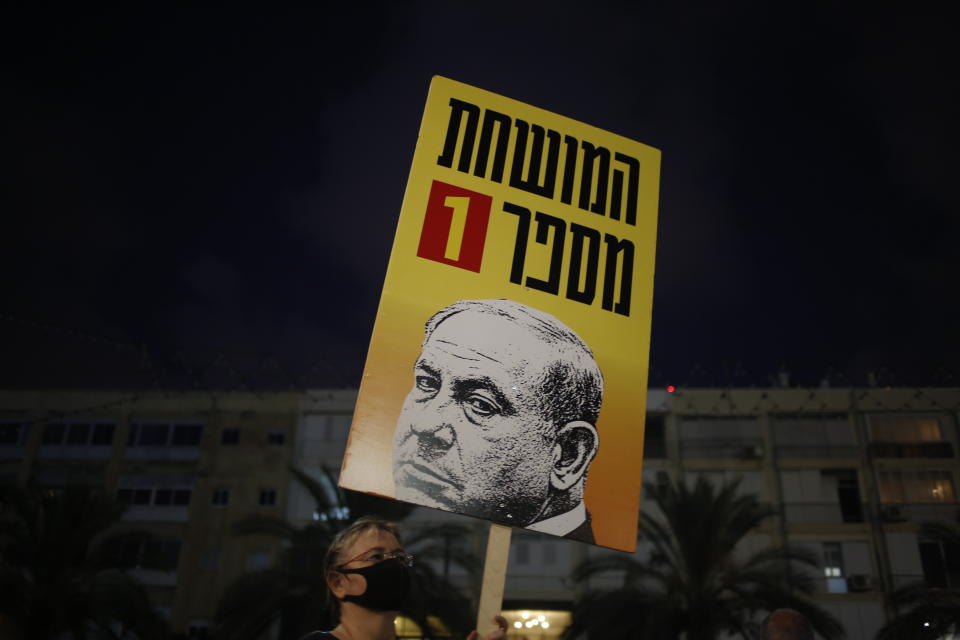 Protesters hold signs during a demonstration against Israel's government in Rabin square in Tel Aviv, Israel, Saturday, July 11, 2020. Thousands of Israelis gathered Saturday to protest the new government's failure to address economic woes brought by the coronavirus, directing their anger at Prime Minister Benjamin Netanyahu who is seeing his support plummeting. The sign say "The number 1 corrupt person".(AP Photo/Ariel Schalit)