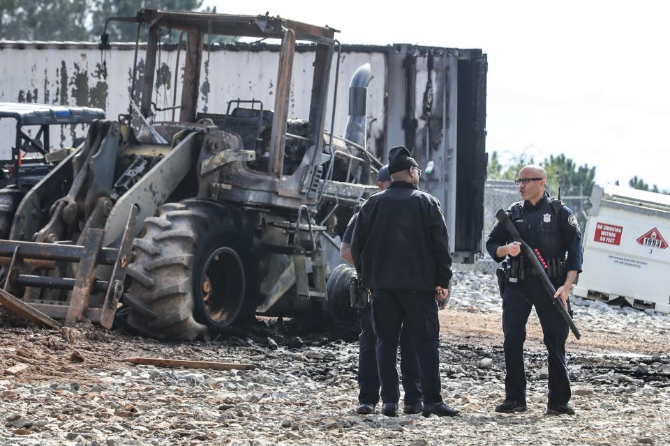 Atlanta police and construction personnel stand near damaged property at the Atlanta Public Safety Training Center in DeKalb County, Ga., Monday, March 6, 2023. More than 20 people from around the country faced domestic terrorism charges Monday after dozens of young men in black masks attacked the site of a police training center under construction in a wooded area outside Atlanta where one protester was killed in January. (John Spink/Atlanta Journal-Constitution via AP)