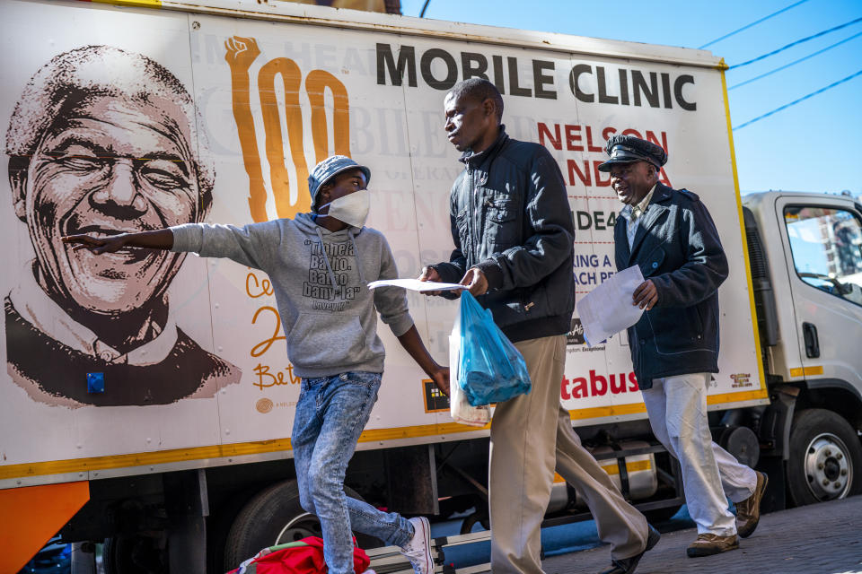 Un voluntario dirige a dos personas hacia un puesto médico móvil llamado Nelson Mandela para que se hagan pruebas de coronavirus, VIH y tuberculosos el 30 de abril del 2020 en Johannesburgo. (AP Photo/Jerome Delay)