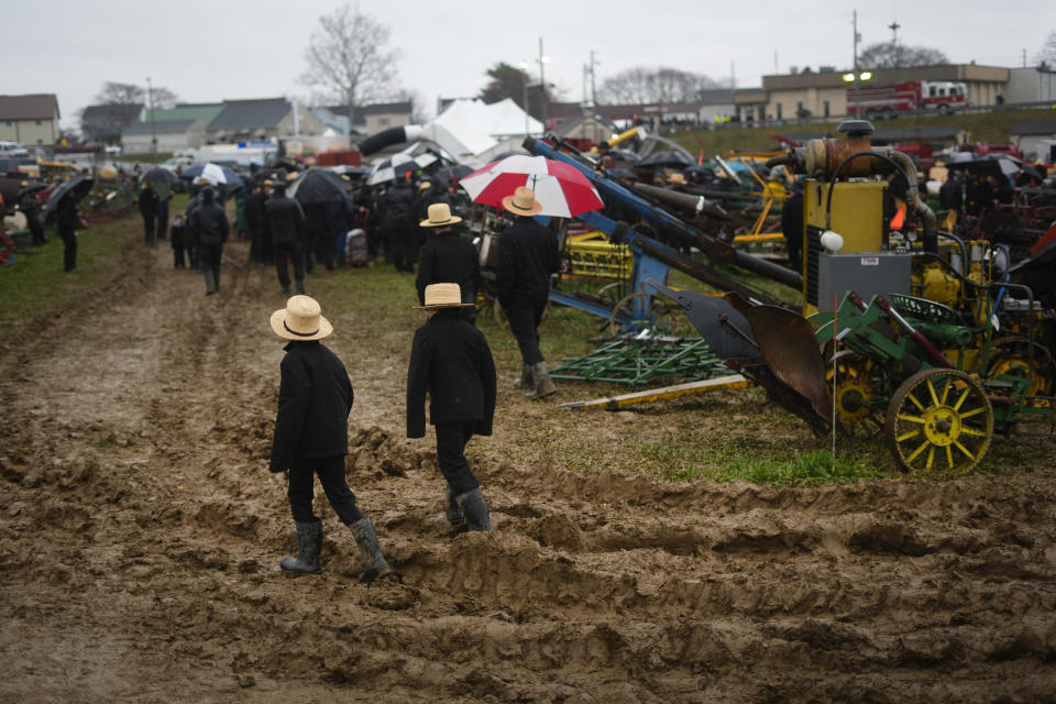 People walk in mud during an auction at the 56th annual mud sale to benefit the local fire department in Gordonville, Pa., Saturday, March 9, 2024. Mud sales are a relatively new tradition in the heart of Pennsylvania's Amish country, going back about 60 years and held in early spring as the ground begins to thaw but it's too early for much farm work. (AP Photo/Matt Rourke)