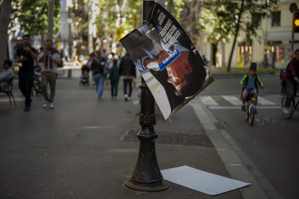 People walk past electoral posters showing a portrait of Catalonia's former regional president Carles Puigdemont in downtown Barcelona, Spain, Thursday, May 9, 2024. Carles Puigdgemont, Catalonia's fugitive former leader, stares confidently out the backseat window of a car, the sun illuminating his gaze in a campaign poster for Sunday's critical elections in the northeastern Spanish region. Some nearly 6 million Catalans are called to cast ballots in regional elections on Sunday that will surely have reverberations in Spain's national politics. (AP Photo/Emilio Morenatti)