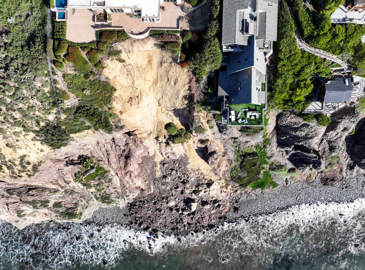Cliff-top houses along Scenic Drive sit close to a landslide in Dana Point, Calif., on Tuesday, Feb. 13, 2024. The three homes affected by the recent deluge of rain across Orange County are being monitored but don't appear to be in imminent danger, county officials said.