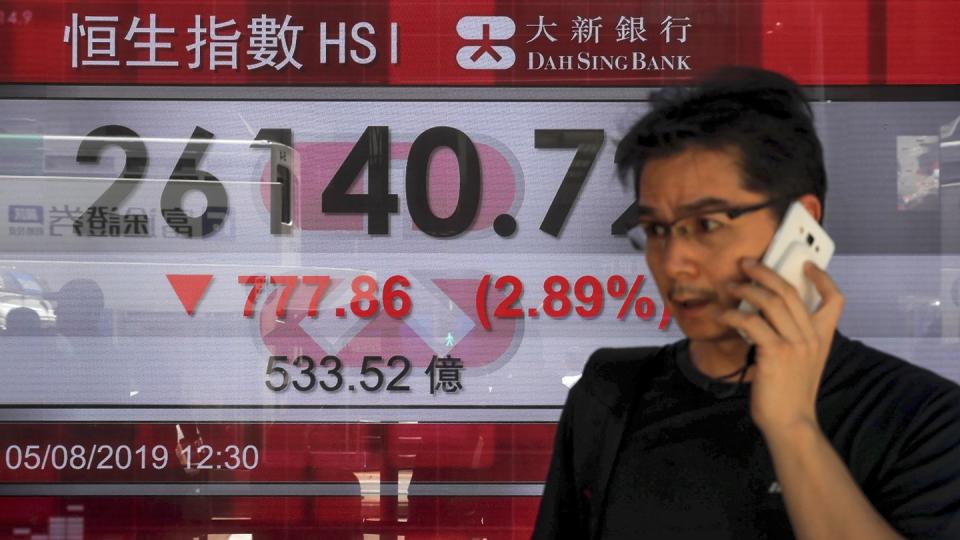 Ein Mann telefoniert in Hongkong vor einer Anzeigetafel mit dem Hong Kong Composite Index. Foto: Kin Cheung/AP