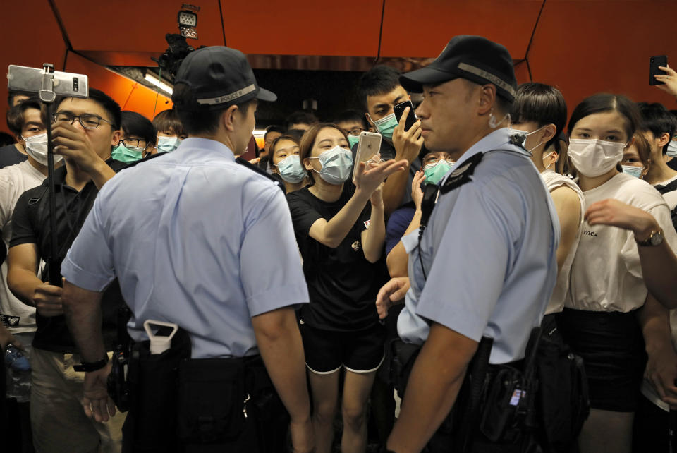 Two Police officers are surrounded by protesters at a subway platform in Hong Kong Tuesday, July 30, 2019. Protesters in Hong Kong have disrupted subway service during the morning commute by blocking the doors on trains, preventing them from leaving the stations. (AP Photo/Vincent Yu)