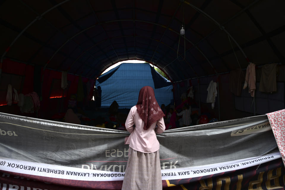 N, a 12-year-old ethnic Rohingya refugee identified by The Associated Press with only an initial, because she is a sexual assault survivor, stands in front of her tent at a temporary shelter in Meulaboh, Indonesia, on Wednesday, April 3, 2024. N was among 75 people rescued from atop an overturned fishing boat off the coast of Indonesia in March. Dozens of other Rohingya refugees died. (AP Photo/Reza Saifullah)