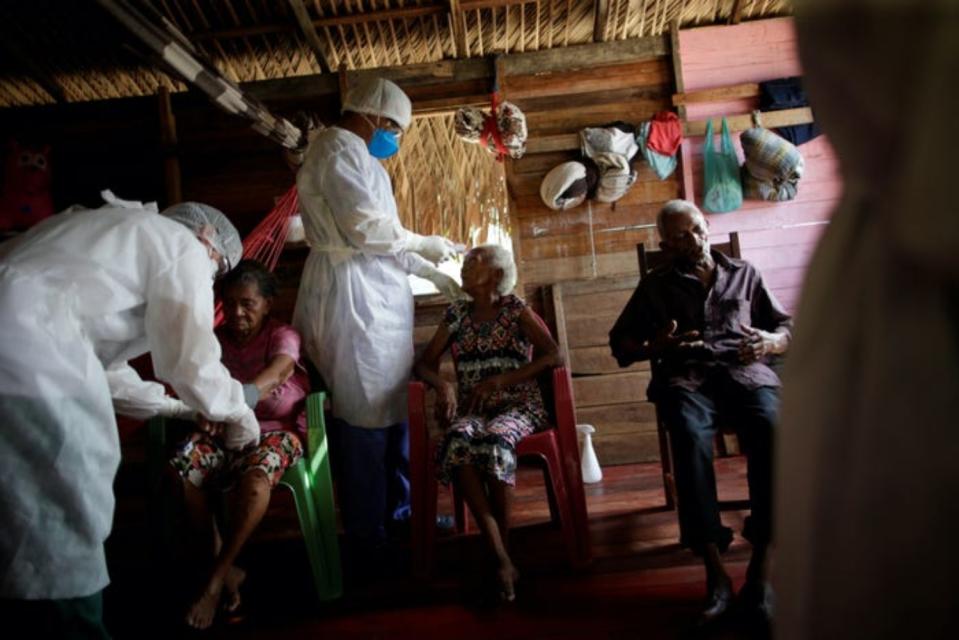 Unos sanitarios visitan a Carmem Silva, de 79 años, Benedeita Vieira Santos, de 105, y Manuel Ferreira Santos, de 96, en la comunidad ribereña de Galileia en la que viven, en el municipio de Melgaco. (Foto: Uesley Marcelino / Reuters).