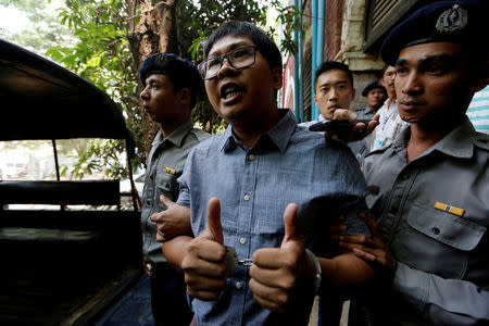 Detained Reuters journalist Wa Lone is escorted by police after a court hearing in Yangon, Myanmar April 4, 2018. REUTERS/Ann Wang/Files