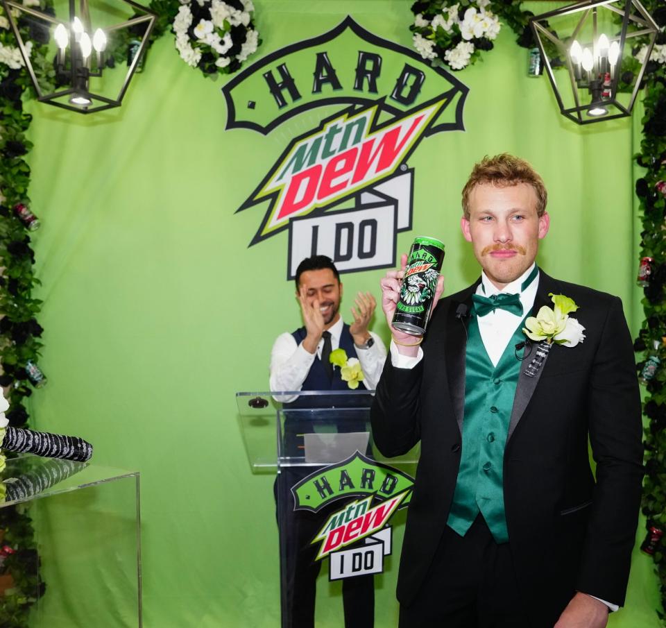 Thoms Rank and a can of Hard Mtn Dew pose in front of the wedding officiant