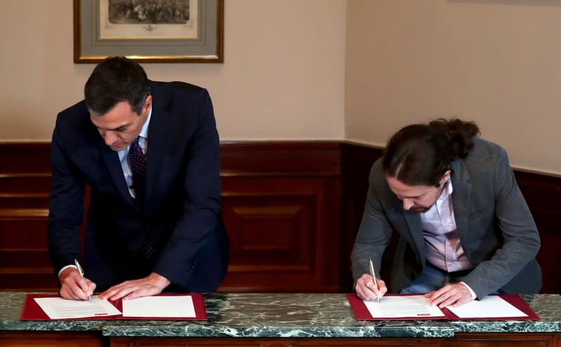 El presidente del gobierno en funciones de España, Pedro Sánchez, y el líder de Unidas Podemos, Pablo Iglesias, firman un acuerdo de coalición durante una conferencia de prensa en el Congreso de los Diputados en Madrid