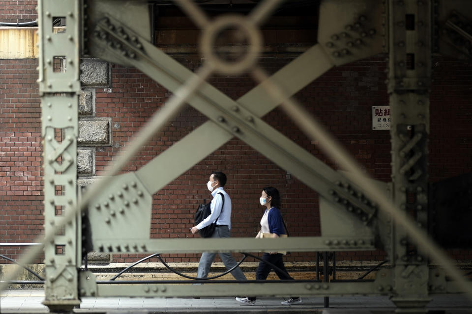 A man and a woman wearing protective masks to help curb the spread of the coronavirus walk along an underpass Tuesday, Sept. 1, 2020, in Tokyo. The Japanese capital confirmed more than 170 coronavirus cases on Tuesday. (AP Photo/Eugene Hoshiko)