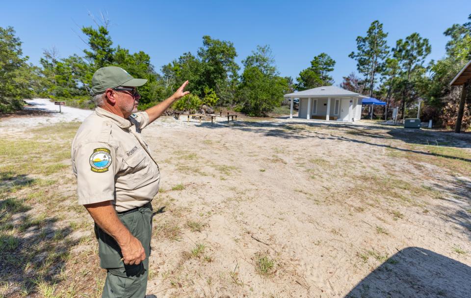 St. Andrews State Park Manager Scott Robinson walks through the new primitive youth group campground that is now open at the park. The campground has been closed since it was heavily damaged in Hurricane Michael.