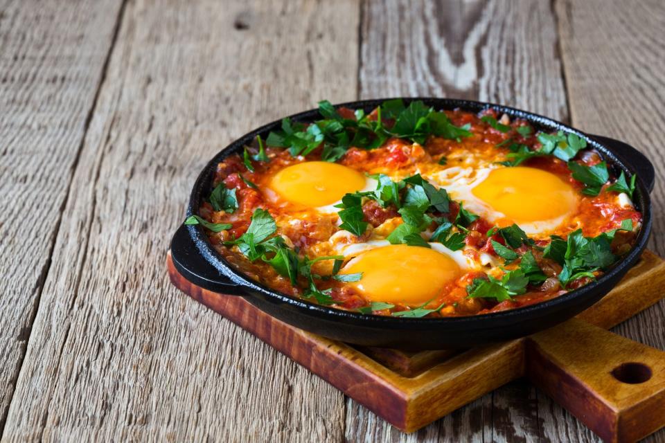"Shakshuka" ist eine Spezialität, die vor allem aus der nordafrikanischen und israelischen Küche bekannt ist. Für dieses Gericht wird eine Soße aus Zwiebeln, Knoblauch, Paprika, Kreuzkümmel, Paprikapulver und einer Dose Tomaten in einer Pfanne gekocht. Im Anschluss Eier aufschlagen und auf die Soße geben. Im Ofen backt das Gericht, bis die Eier gestockt sind. (Bild: iStock/istetiana)