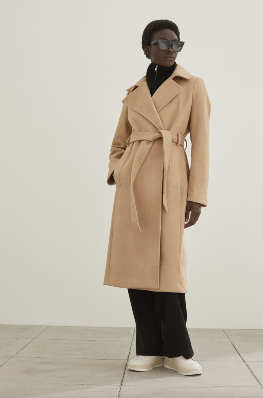 black model with short hair wearing camel Tie Belt Coat, black pants, and white shoes