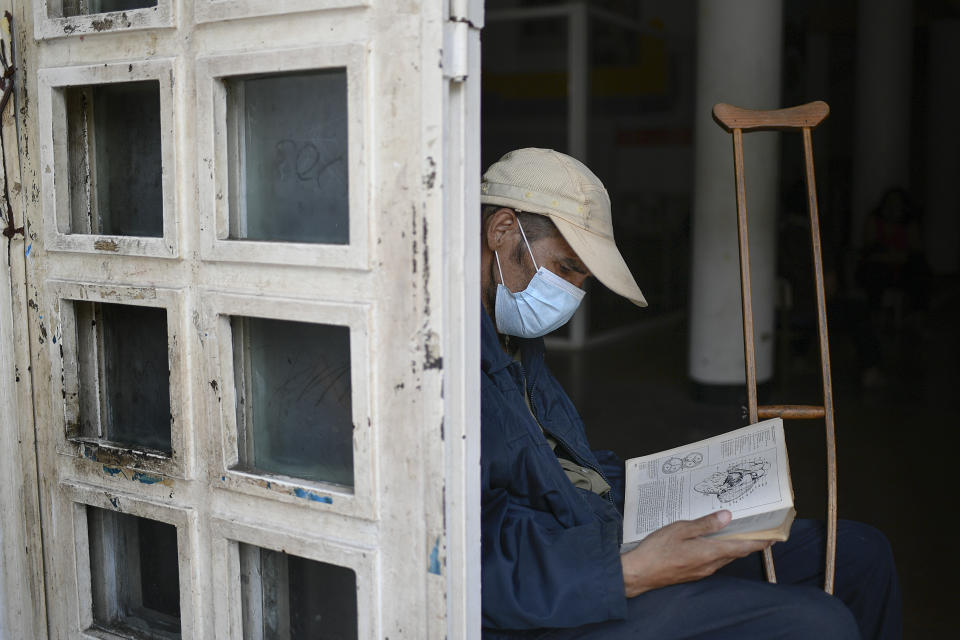 An elderly man who uses a crutch due to having lost half his leg reads a book at a cultural center in La Pastora neighborhood of Caracas, Venezuela, Monday, June 29, 2020, amid the COVID-19 pandemic. (AP Photo/Matias Delacroix)
