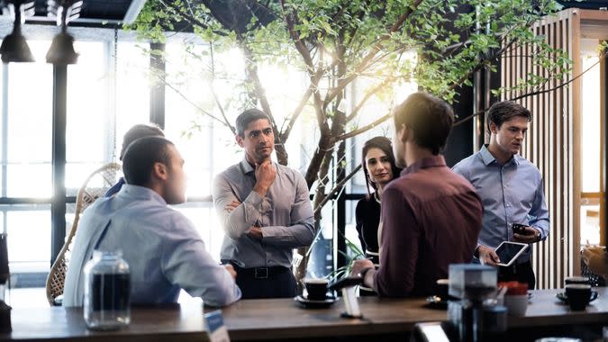 Businessman discussing with colleagues at office cafeteria.