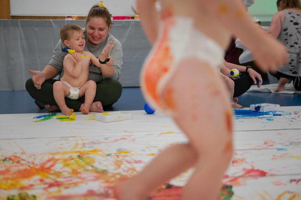 Katheryn Charles and her two-year-old son Harrison Charles play with a paint sponge during the baby paint crawl.