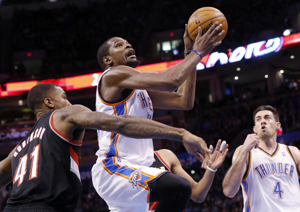 Oklahoma City Thunder forward Kevin Durant, center, shoots in front of Portland Trail Blazers forward Thomas Robinson (41) and teammate Nick Collison (4) in the third quarter of an NBA basketball game in Oklahoma City, Tuesday, Jan. 21, 2014. Oklahoma City won 105-97. (AP Photo/Sue Ogrocki)
