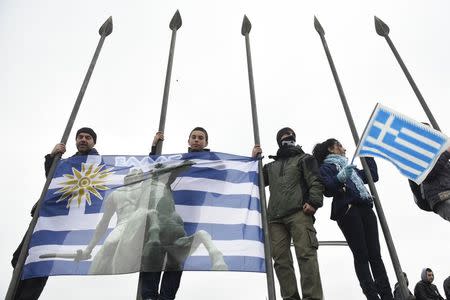 Protesters hold a Greek national flag depicting Alexander the Great as they stand on a monument during a rally against the use of the term "Macedonia" in any solution to a dispute between Athens and Skopje over the former Yugoslav republic's name, in the northern city of Thessaloniki, Greece, January 21, 2018. REUTERS/Alexandros Avramidis