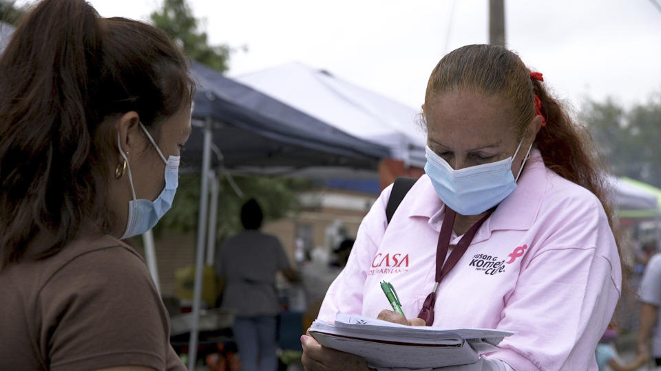 A "promotora" (health promoter) from CASA, a Hispanic advocacy group, tries to enroll Latinos as volunteers to test a potential COVID-19 vaccine, at a farmers market in Takoma Park, Maryland on Sept. 9, 2020. Minority enrollment in studies of two shots has inched up in recent weeks, but even more is needed this fall as additional vaccine testing gets underway over the next two months. (AP Photo/Federica Narancio)