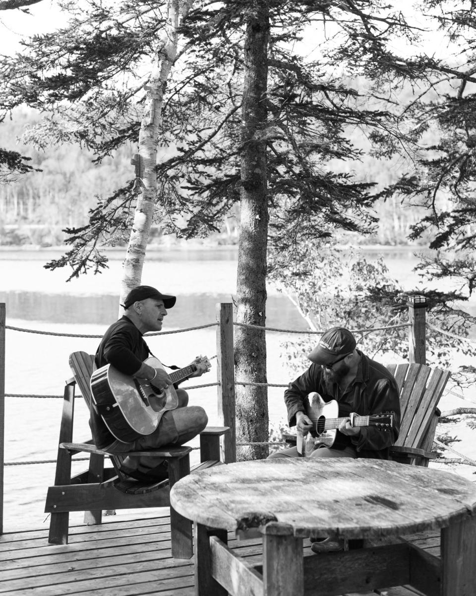 Angelo sings and plucks with Picard on the deck of his kayak tour business.