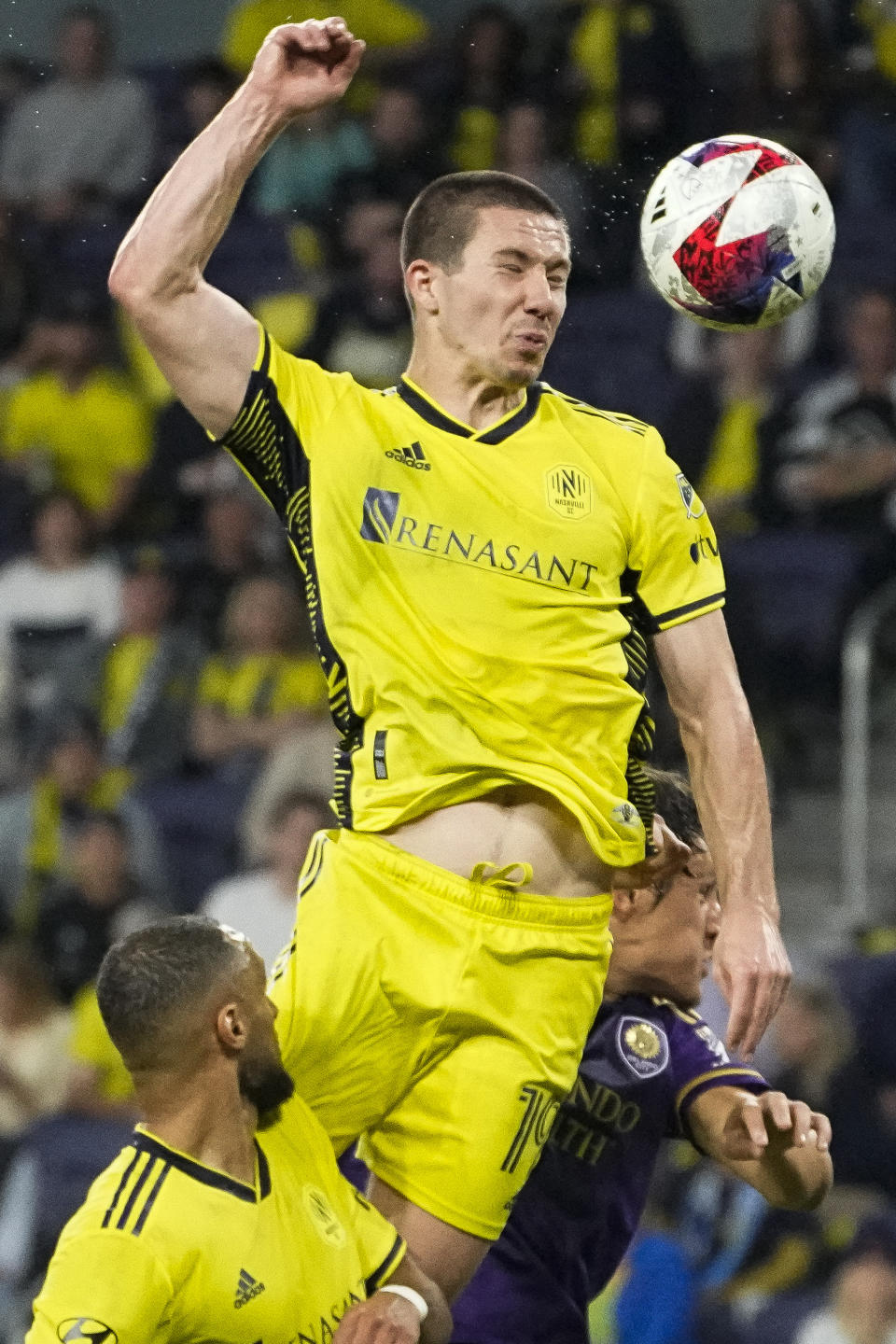 Nashville SC midfielder Alex Muyl, center, heads the ball over teammate midfielder Hany Mukhtar, left, and Orlando City defender Rodrigo Schlegel, right, during the first half of an MLS playoff soccer match Tuesday, Nov. 7, 2023, in Nashville, Tenn. (AP Photo/George Walker IV)