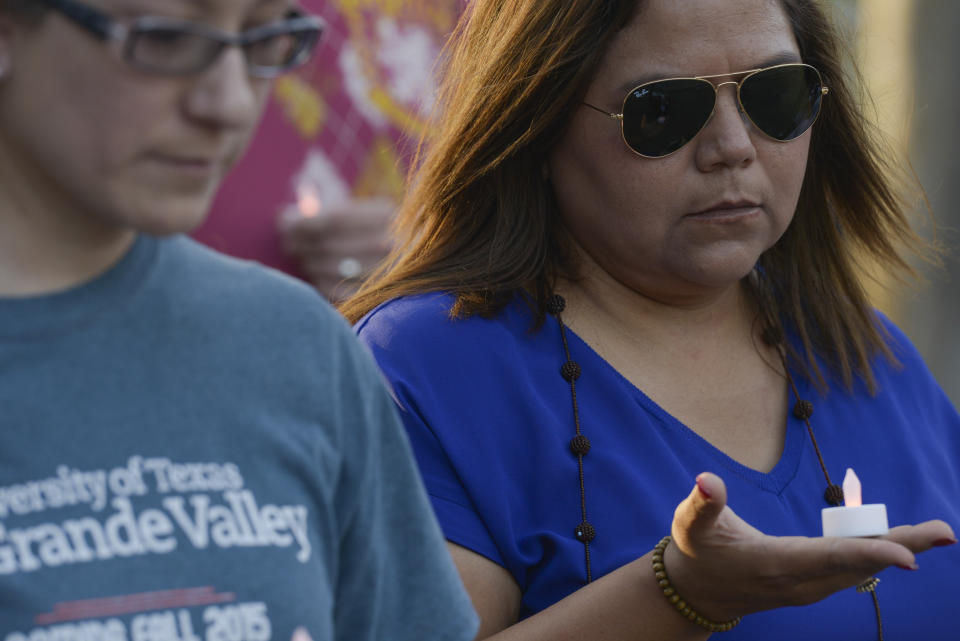 Celia Hernandez holds her candle in the palm of her hand during a moment of silence for the 22 victims of the recent El Paso shooting during a vigil Sunday, Aug. 11, 2019, at Alice Wilson Hope Park in Brownsville, Texas.(Denise Cathey/The Brownsville Herald via AP)