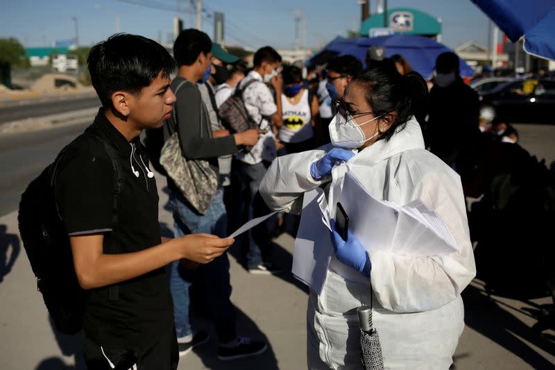 Personnel of an assembly factory, in protective gear, talk to job seekers as the coronavirus disease (COVID-19) outbreak continues in Ciudad Juarez