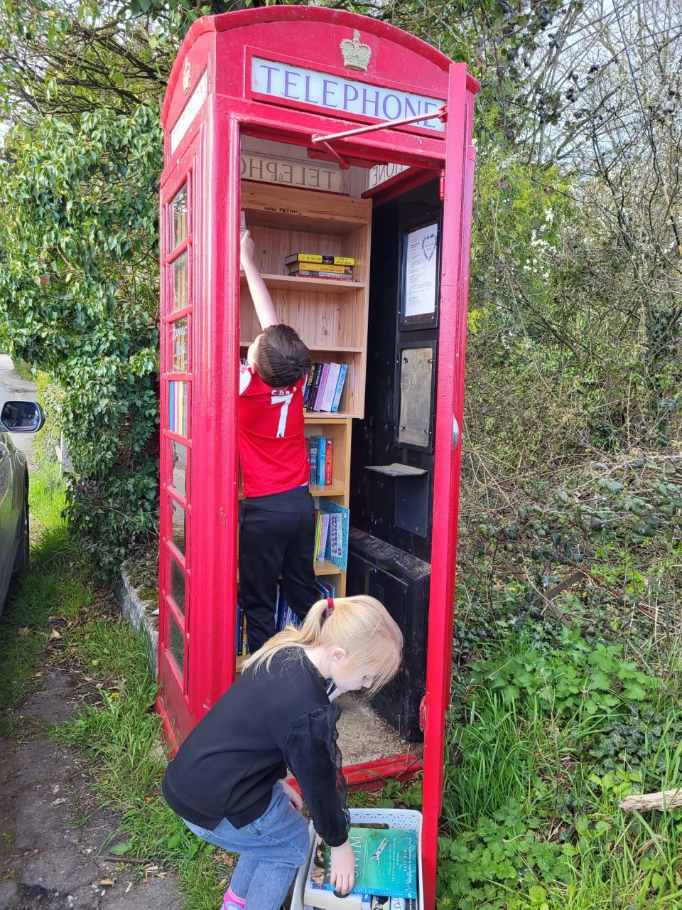 People putting books in telephone box