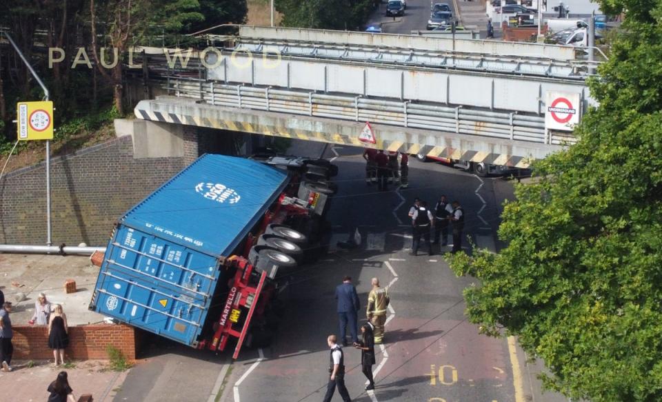 Road blocked after lorry hits bridge and overturns in east London