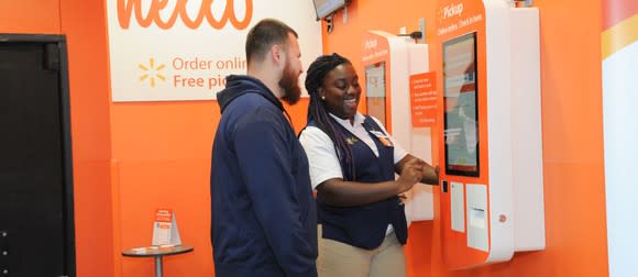 Walmart associate assisting a customer at a pickup tower.