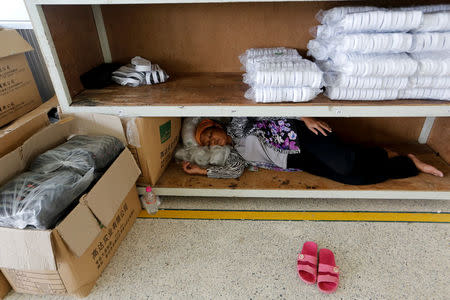 A worker has a nap on a shelf during a lunch break at Complete Honour Footwear Industrial, a footwear factory owned by a Taiwan company, in Kampong Speu, Cambodia, July 5, 2018. REUTERS/Ann Wang