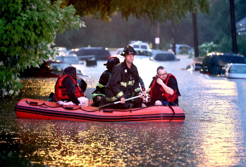 Steven Bertke and his dog Roscoe are taken to dry land by St. Louis firefighters who used a boat to rescue people from their flooded homes on Hermitage Avenue in St. Louis on Tuesday, July 26, 2022.