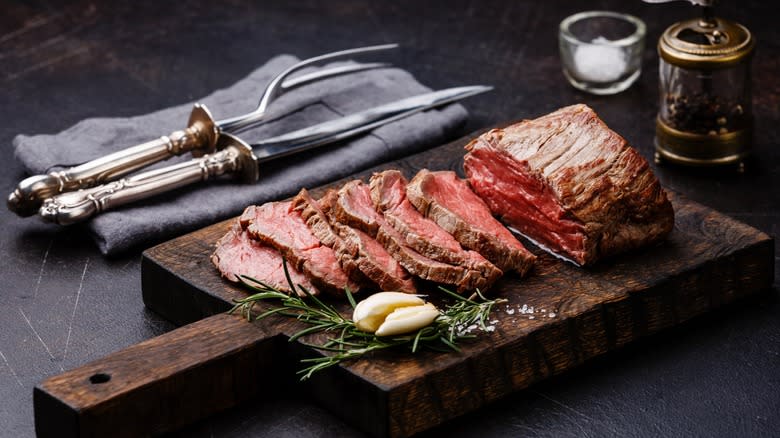 A sliced beef tenderloin served on a wooden board