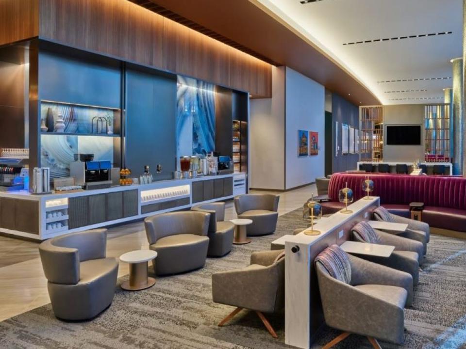 Delta's Sky Club at ORD with red couches and beige chairs with a drink stand in the background.